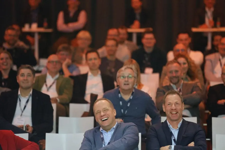 Lachendes Konferenzpublikum im abgedunkelten Saal