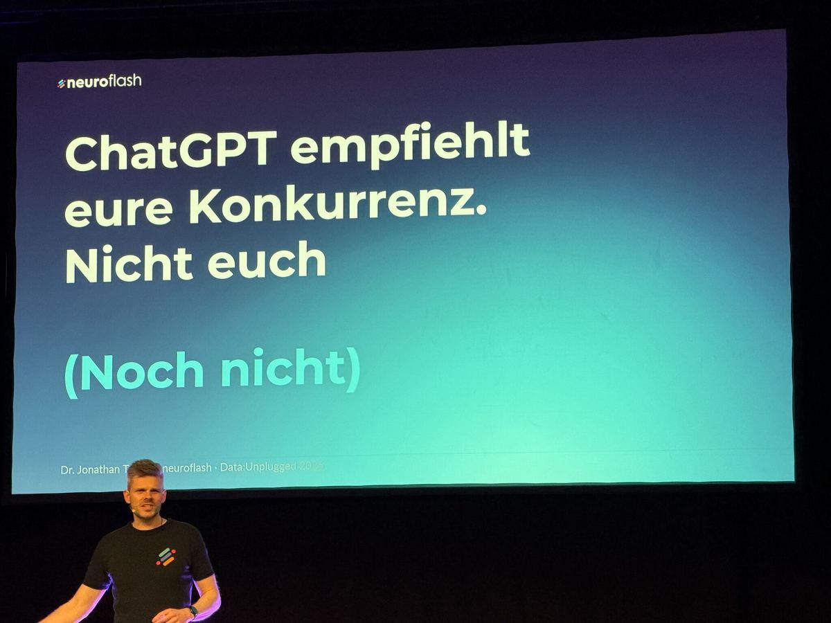 Keynote-Folie &bdquo;ChatGPT empfiehlt eure Konkurrenz. Nicht euch. (Noch nicht)&ldquo; &mdash; Dr. Jonathan Mall auf der B&uuml;hne darunter