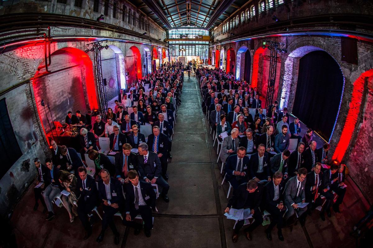 Großes Publikum in einer Industriehalle bei einer Konferenz-Keynote